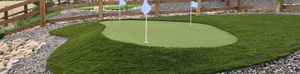 Backyard putting green with three flags and rock border in Denver