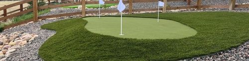 Backyard artificial putting green with three flags and rock border in a Denver yard