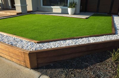 Artificial turf area bordered by a raised wood planter and rock